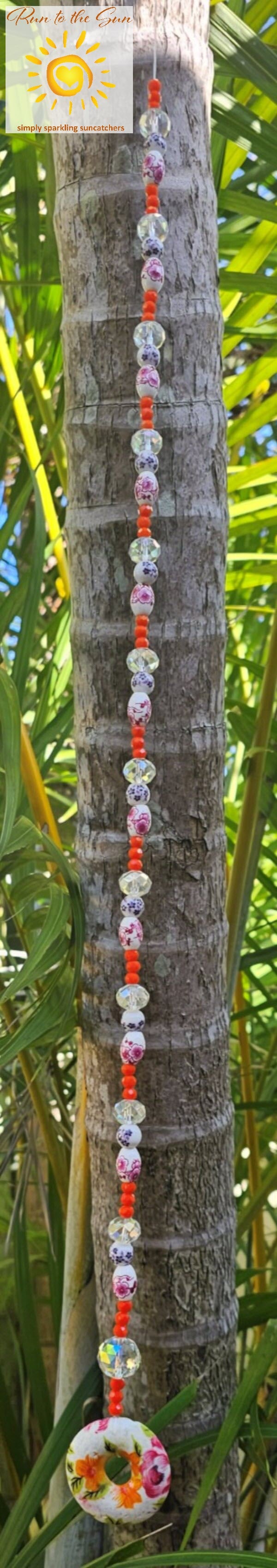 Ceramic donut Pendant Suncatcher with pink, blue and orange beads hanging view